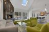 Living area featuring a skylight, visible vents, a premium fireplace, wood finished floors, and high vaulted ceiling