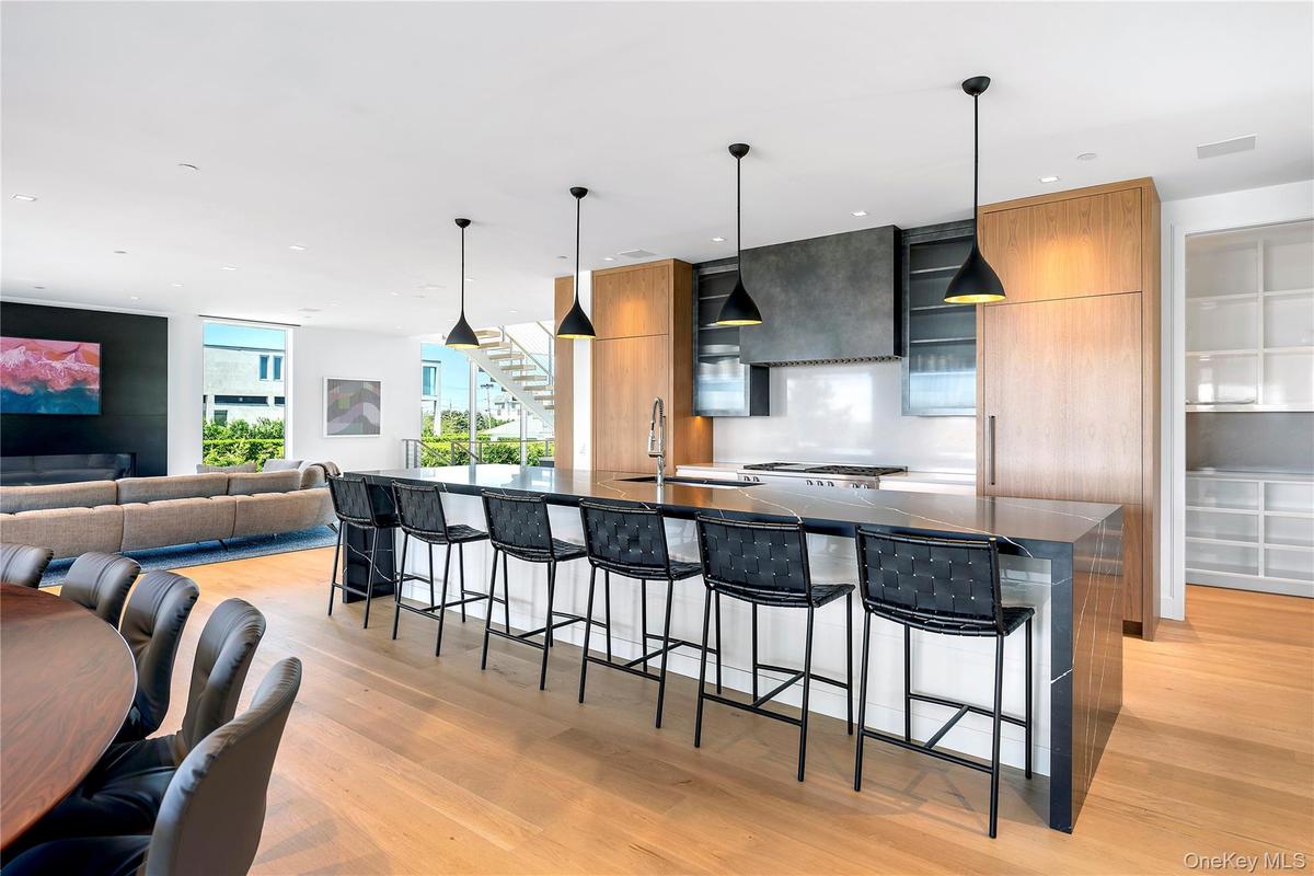 Kitchen with modern cabinets, a breakfast bar, decorative light fixtures, a large island, and light wood finished floors
