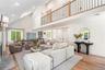 Living area with a fireplace, a towering ceiling, light wood-type flooring, recessed lighting, and healthy amount of natural light