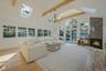 Living room with beamed ceiling, light hardwood / wood-style flooring, high vaulted ceiling, and a tiled fireplace