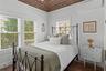 Bedroom with an AC wall unit, multiple windows, and wood finished floors