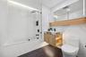Bathroom with toilet, a combined bath / shower with marble appearance, and vanity