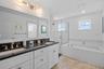 Top floor bathroom with soaking tub, walk in shower, and dual vanity