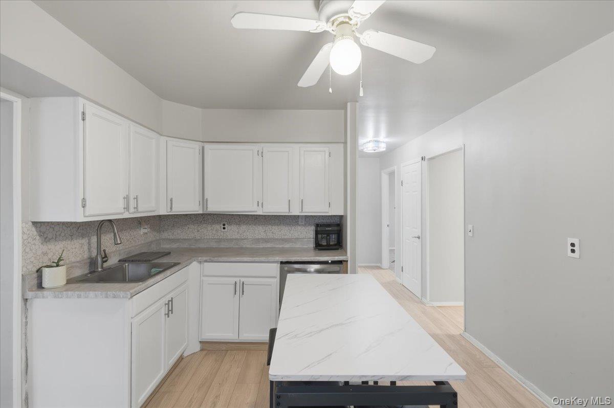 Kitchen with white cabinets, decorative backsplash, and light countertops
