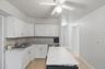 Kitchen with white cabinets, decorative backsplash, and light countertops