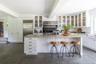 Kitchen with light stone countertops, a kitchen breakfast bar, white cabinets, finished concrete flooring, and a kitchen island with sink