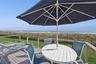 Deck with outdoor dining space, a lawn, and view of water and beach