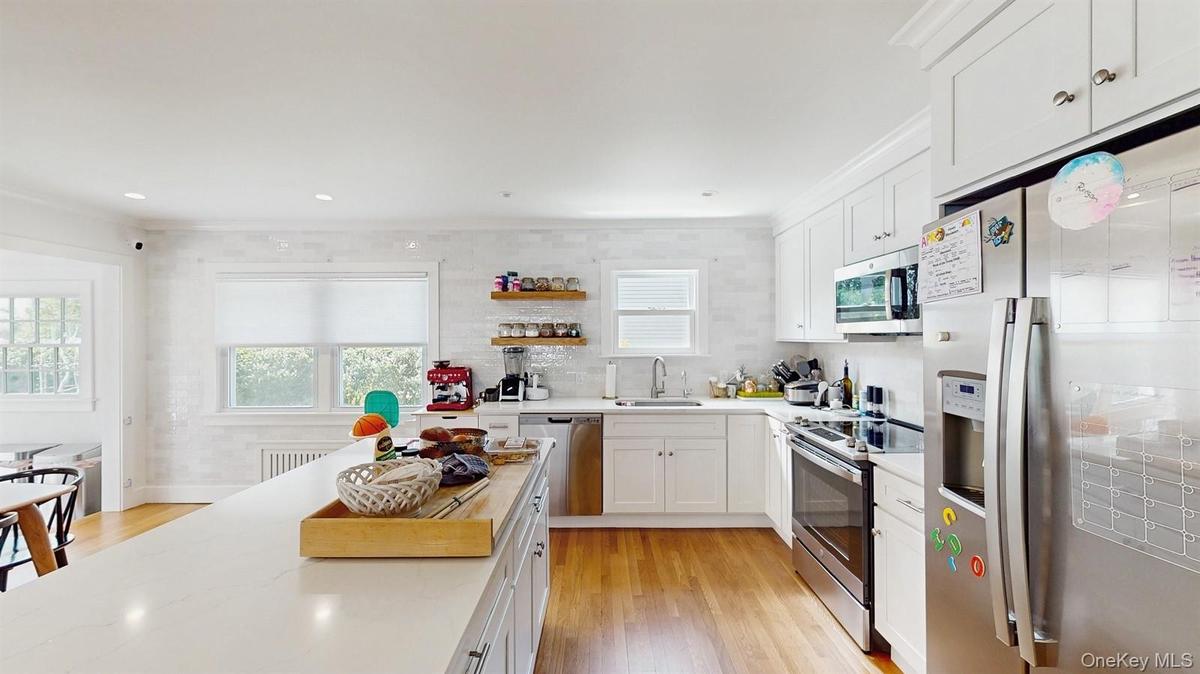 Kitchen with a sink, white cabinets, appliances with stainless steel finishes, and a healthy amount of sunlight