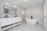 Bathroom featuring stone wall, a soaking tub, recessed lighting, double vanity, and light marble finish floors