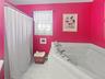 Full bath with a tub with jets, tile patterned floors, and a baseboard heating unit