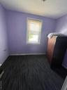 Unfurnished bedroom featuring dark wood-type flooring and baseboards