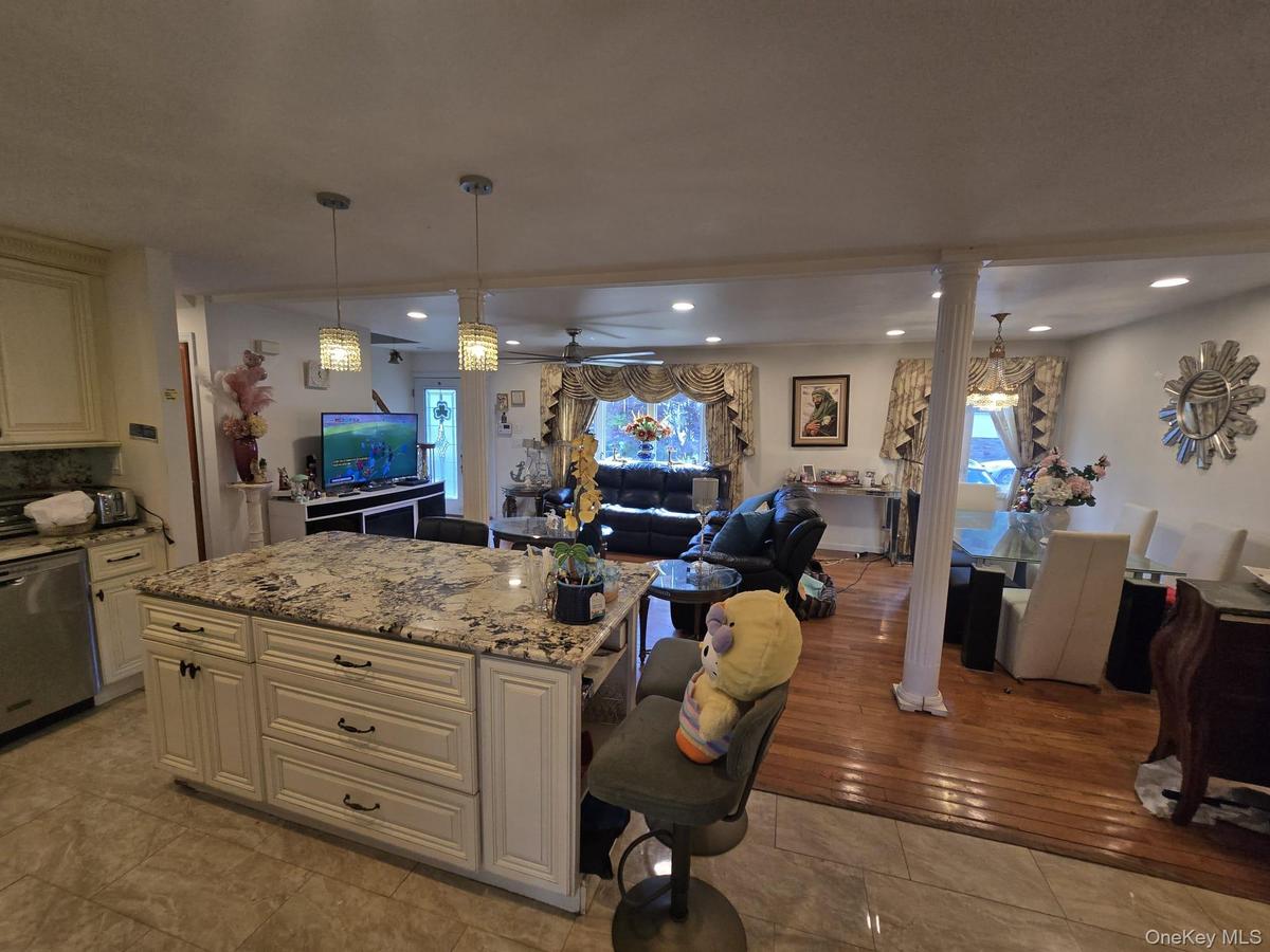 Kitchen island featuring a patterned countertop with pendant lighting, integrated cabinetry, and tiled flooring