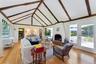 Living room with healthy amount of natural light, light wood-style floors, high vaulted ceiling, beam ceiling, and a brick fireplace