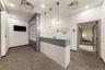 Modern reception area featuring a built-in white and gray reception desk, three gold-toned pendant lights, and textured gray carpeting