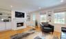 Living room with built in features, a high end fireplace, and light hardwood / wood-style floors