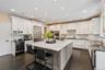 Kitchen with dark stone counters, tasteful backsplash, dark wood-type flooring, white cabinets, and recessed lighting