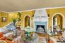 Formal living room looking towards formal dining room, featuring floor to ceiling fireplace, solid wood floors, crown molding, terra cotta tile prince