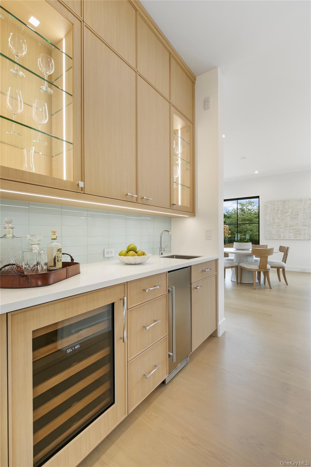 Bar area with glass insert cabinets, backsplash, beverage cooler, light brown cabinetry, and recessed lighting