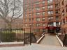 Brick facade building featuring multiple window styles, a covered main entrance, and decorative wrought iron fencing