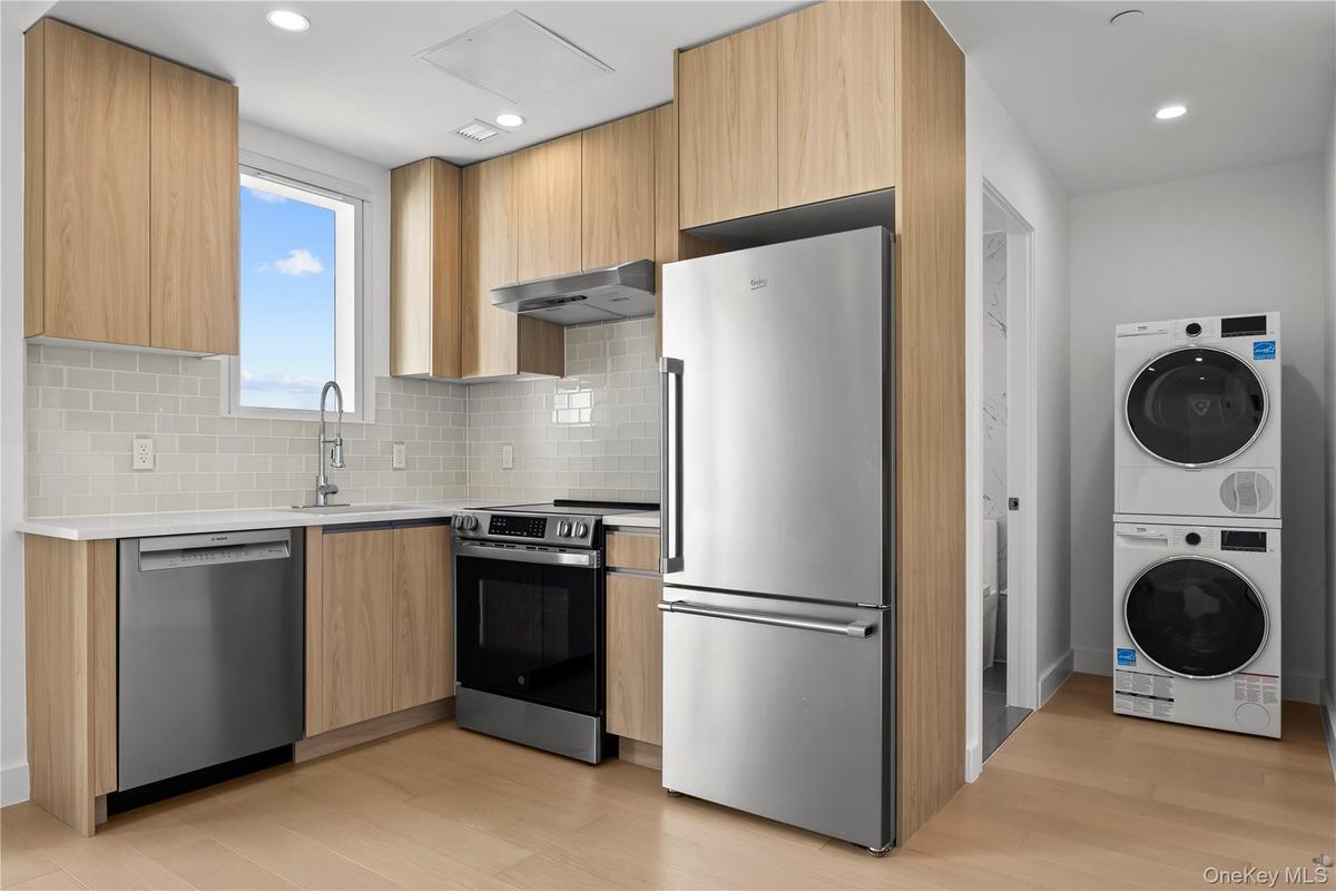 Kitchen with stainless steel appliances, modern cabinets, light wood-type flooring, light stone counters, and recessed lighting
