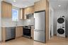 Kitchen with stainless steel appliances, modern cabinets, light wood-type flooring, light stone counters, and recessed lighting