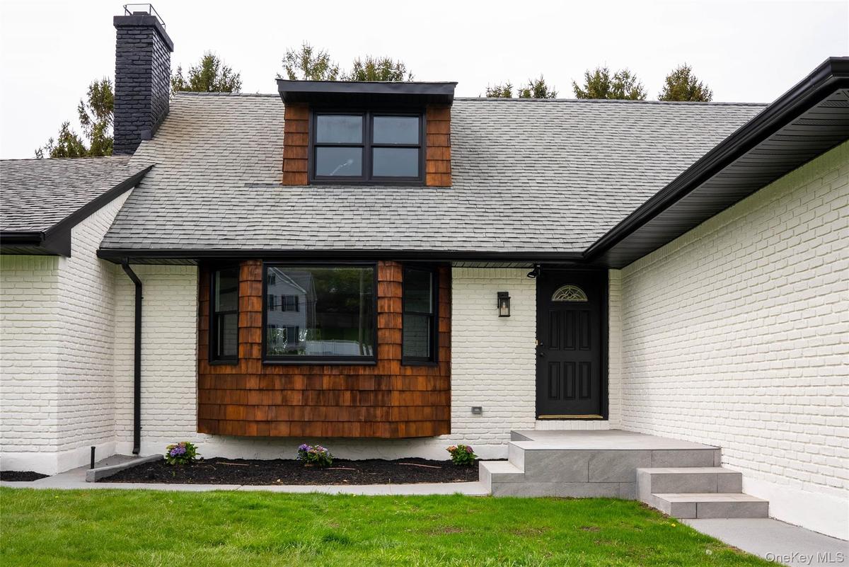 View of front of property featuring a chimney, a shingled roof, and a front lawn