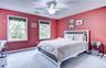 Spacious bedroom featuring neutral-toned carpet, a ceiling fan with integrated lighting