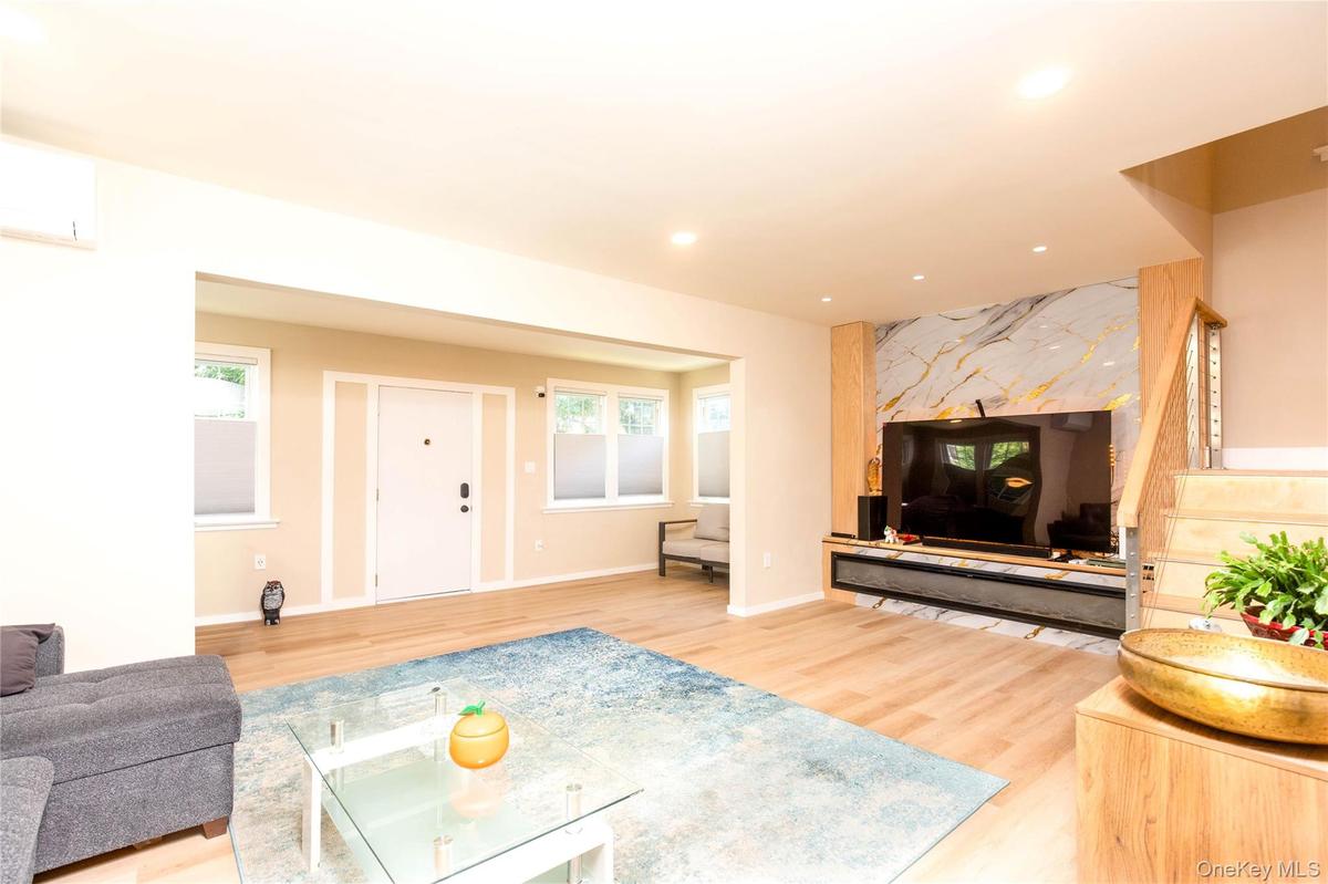 Open-concept living space featuring wood-finish flooring, recessed lighting, and a modern accent wall with a large built-in media console