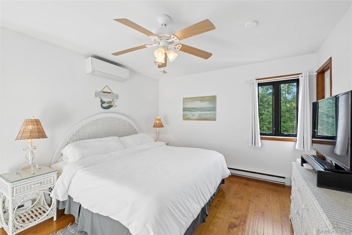 Bedroom featuring wood-finish flooring, white walls, and a ceiling fan with integrated lighting