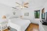 Bedroom featuring wood-finish flooring, white walls, and a ceiling fan with integrated lighting