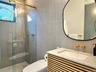 Bathroom with tile walls, a shower stall, toilet, vanity, and tasteful backsplash