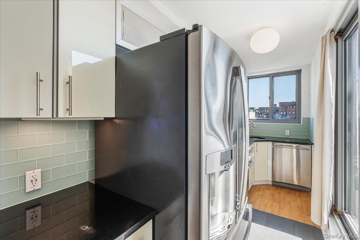 Kitchen featuring decorative backsplash, stainless steel appliances, white cabinetry, and light wood finished floors