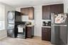 Compact kitchen featuring a stainless steel gas range, dark wood-finish cabinetry, light-colored countertops, and wood-finish flooring