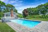 Swimming pool featuring a patio area, a yard, an outdoor living space, a wooden deck, and view of wooded area