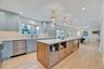 Kitchen featuring decorative light fixtures, open shelves, a kitchen island, light wood-style flooring, and a kitchen breakfast bar