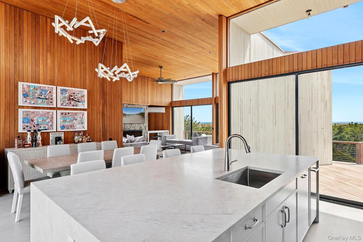 Kitchen with pendant lighting, wooden ceiling, a sink, wooden walls, and a towering ceiling