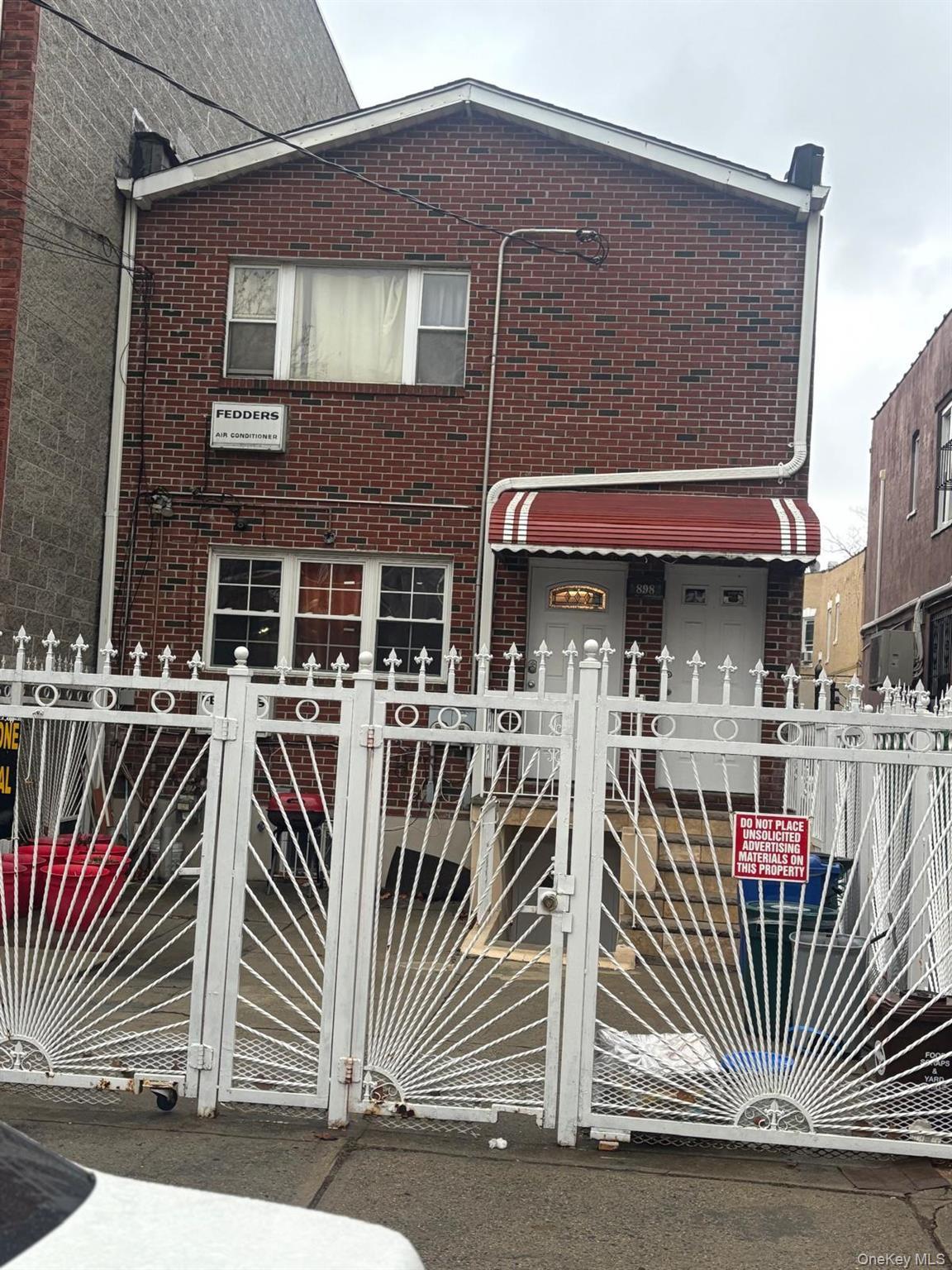 View of front of home featuring brick siding, a fenced front yard, and a gate