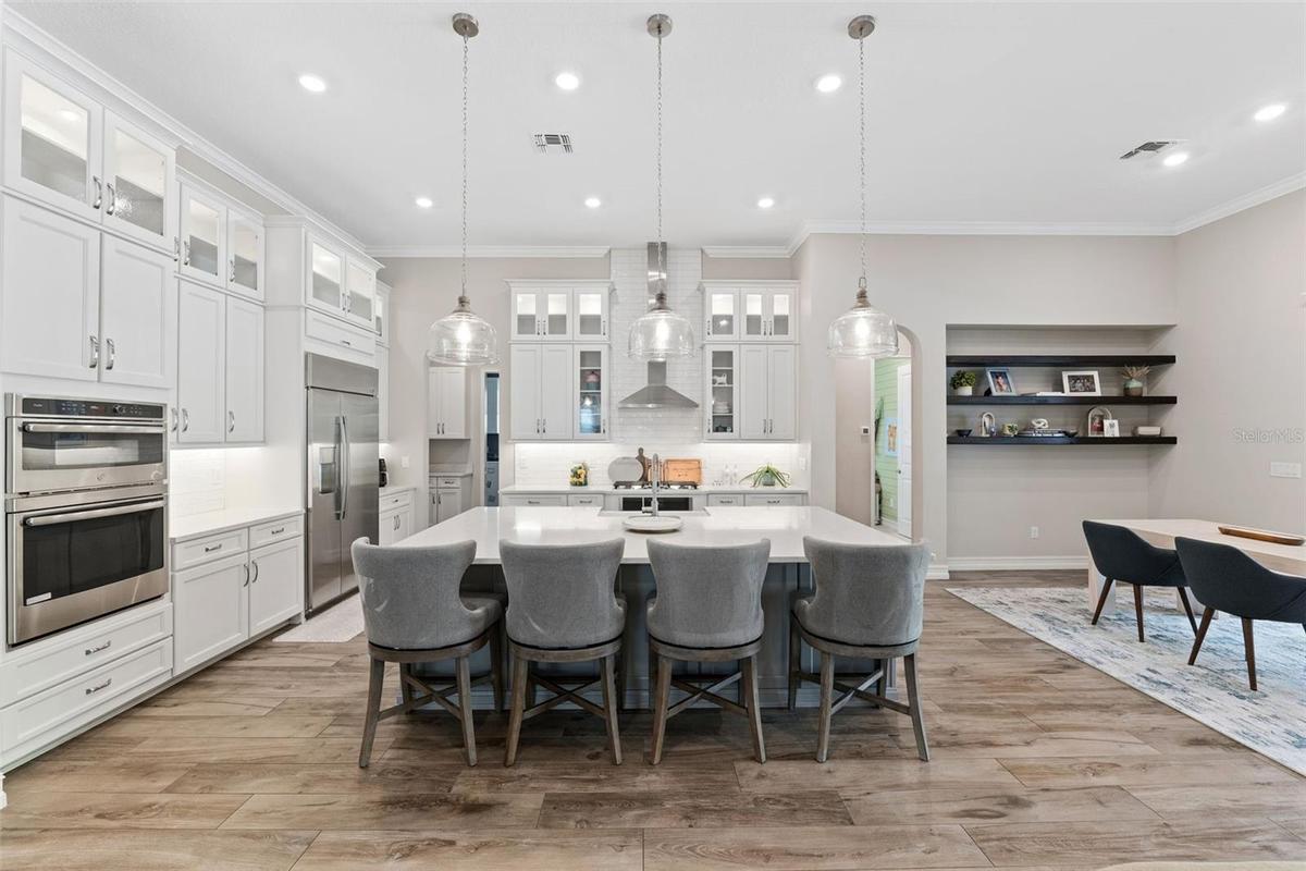Spacious and open gourmet kitchen features built-in oven, cooktop with hood, quartz countertops, built-in lighting and more.