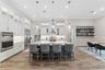 Spacious and open gourmet kitchen features built-in oven, cooktop with hood, quartz countertops, built-in lighting and more.