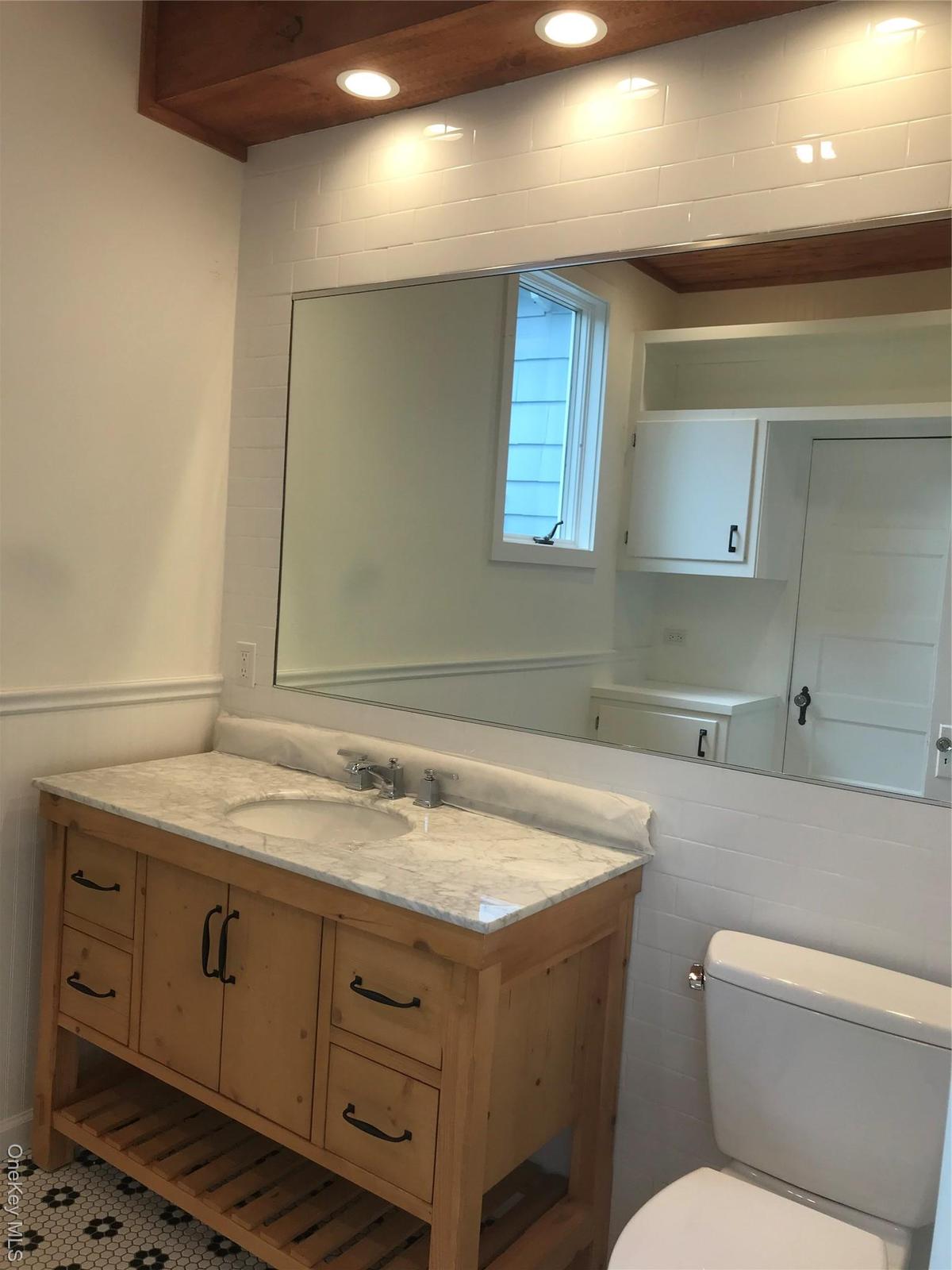 Half bath with recessed lighting, wainscoting, vanity, and toilet