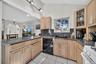 Kitchen featuring dark countertops, light brown cabinets, white range oven, a peninsula, and black dishwasher