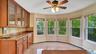 Kitchen featuring brown cabinetry, backsplash, granite finish floor, glass insert cabinets, and baseboards