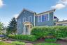 The front exterior of the home (which is perpendicular to the street) offers a timeless look with green siding, crisp trim, lush landscaping, and a we