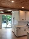 Kitchen with white cabinets, wooden ceiling, light countertops, light wood-type flooring, and backsplash