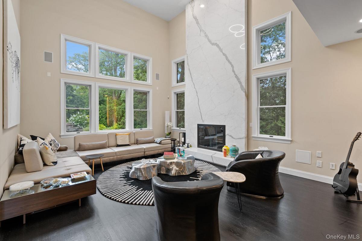 Living room featuring a high ceiling, dark wood-type flooring, and a high end fireplace