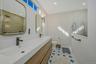 New primary bathroom with tile patterned floors, vanity, toilet, and a tile shower