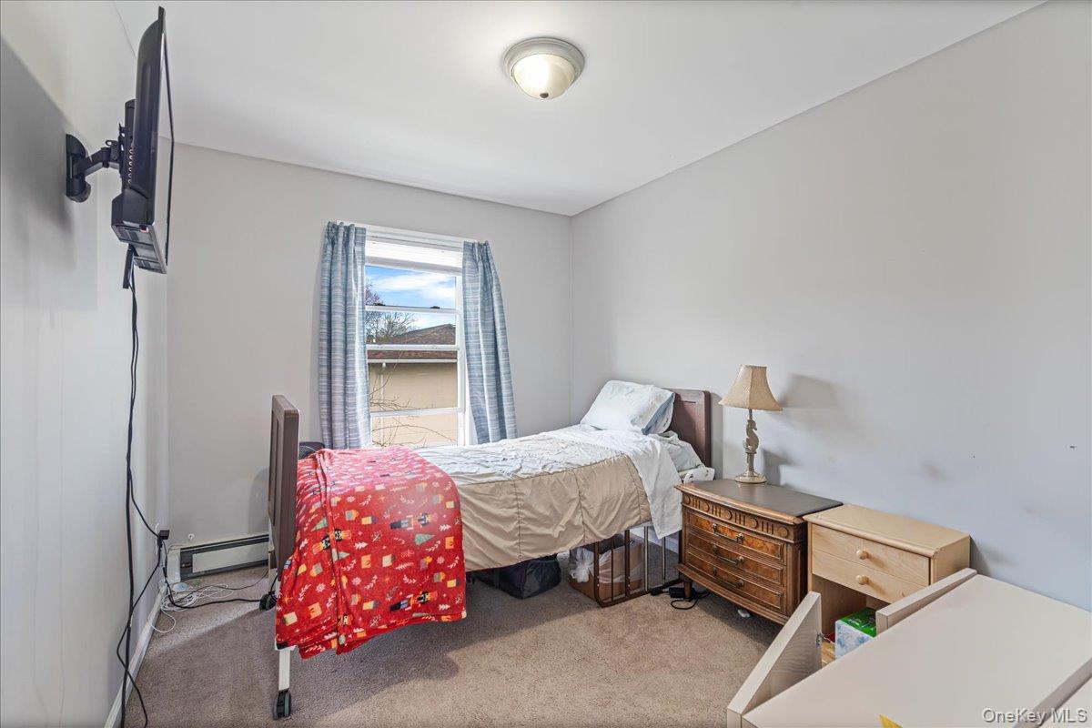 Bedroom room with a wall-mounted light fixture, a window with blue curtains, and light gray walls