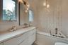 Full bathroom with lofted ceiling, tiled tub, and vanity