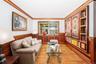 Living area with wainscoting, ornamental molding, wood finished floors, and wood walls