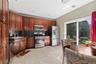 Wood-finish cabinetry with stainless steel appliances, black countertops, and a tile floor